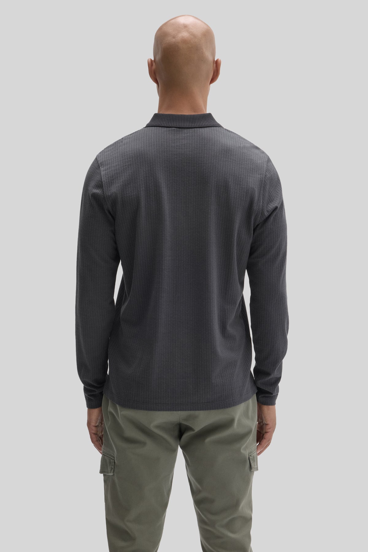 Dark gray long sleeve polo shirt with ribbed collar, shown from back view on model wearing olive cargo pants.