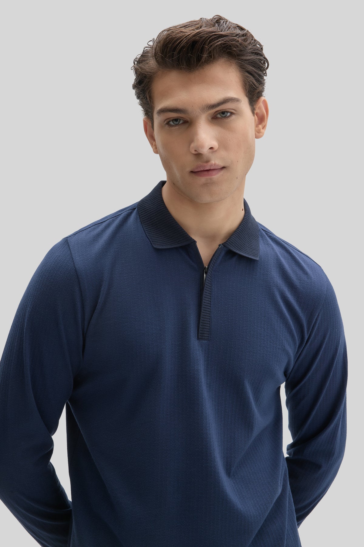 Man wearing navy long sleeve polo shirt with ribbed collar and quarter-zip placket closure.