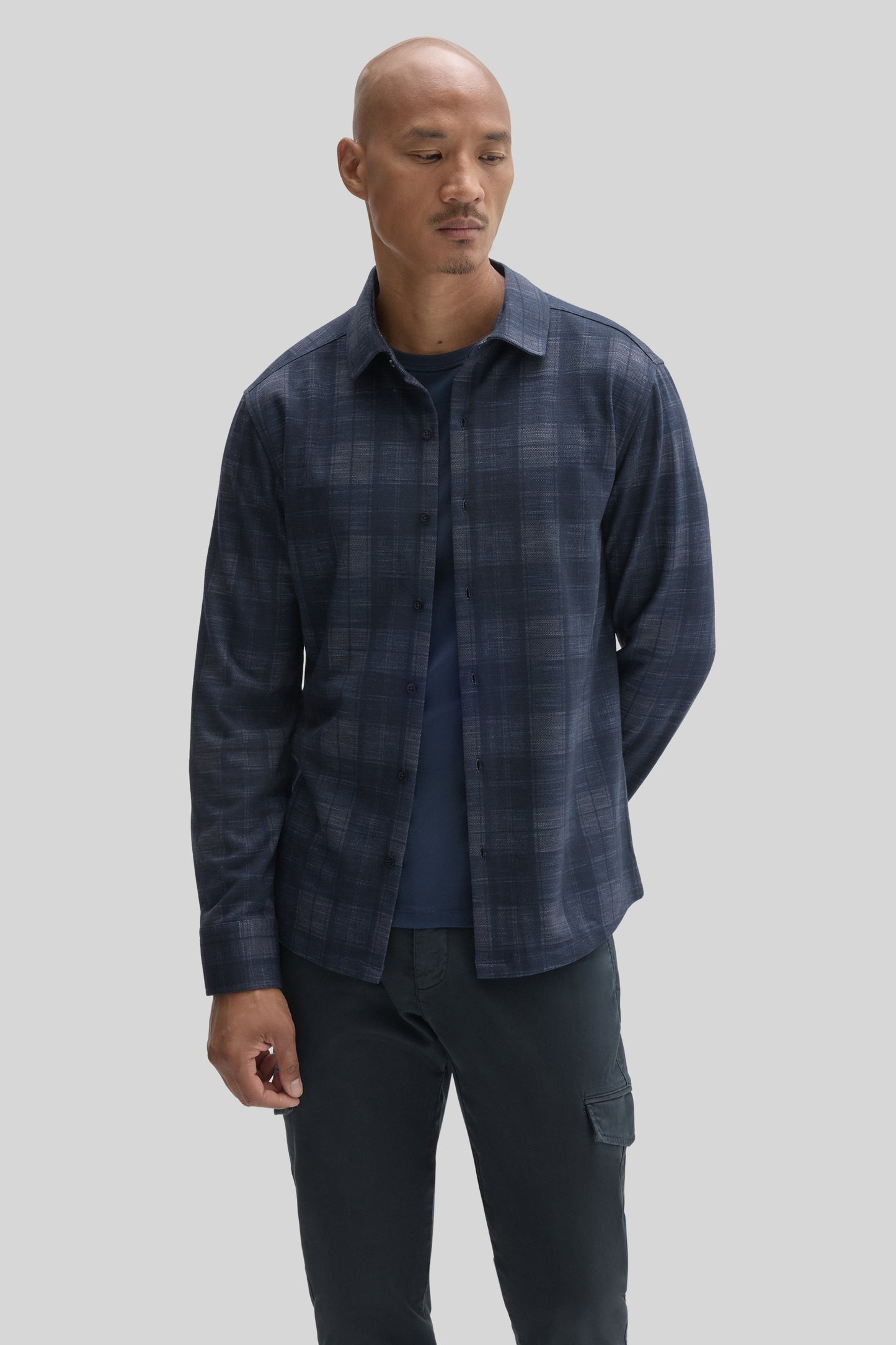 Man wearing navy blue plaid button-up shirt over a dark blue t-shirt with dark cargo pants.
