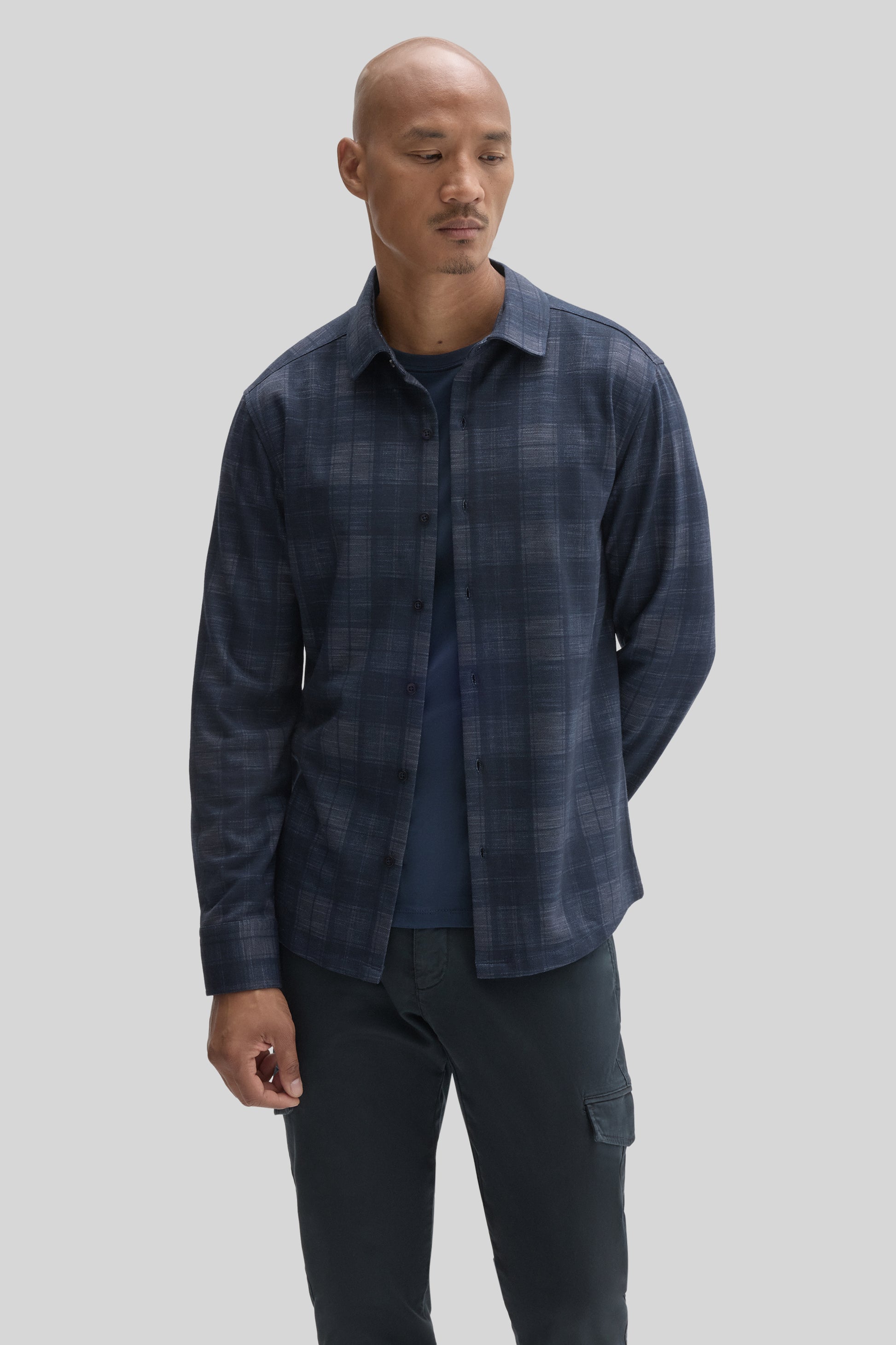 Man wearing navy blue plaid button-up shirt over a dark blue t-shirt with dark cargo pants.