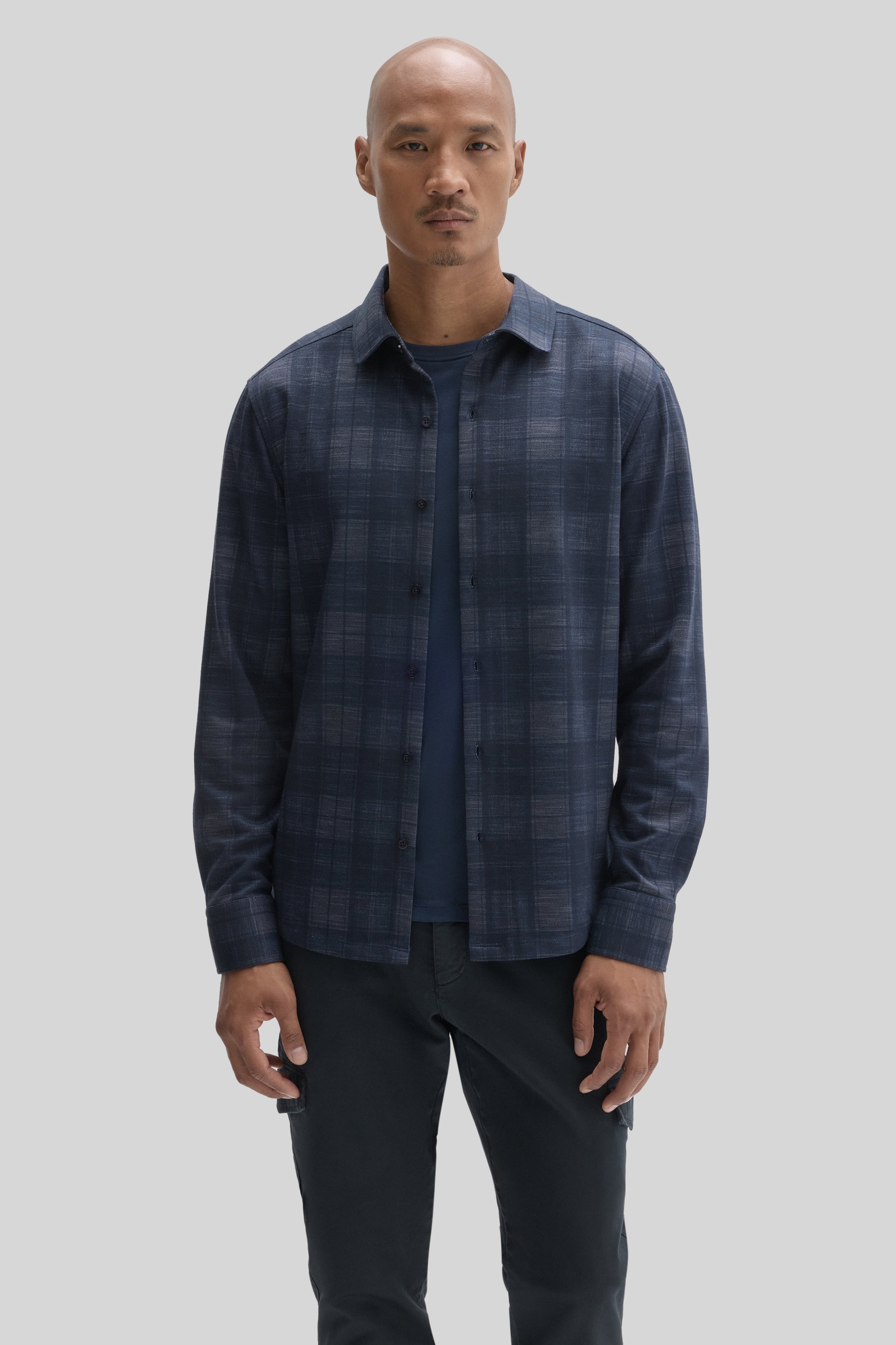 Navy plaid button-up shirt with long sleeves worn over a dark undershirt.