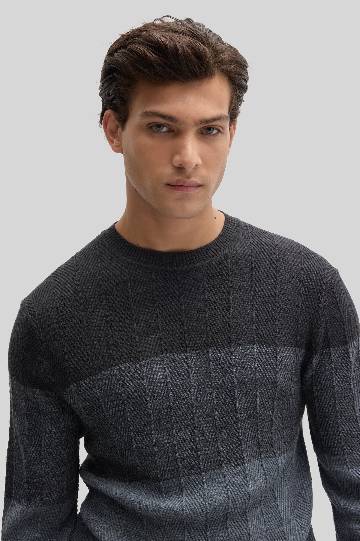Charcoal crewneck sweater with herringbone texture pattern and color-block design on model.