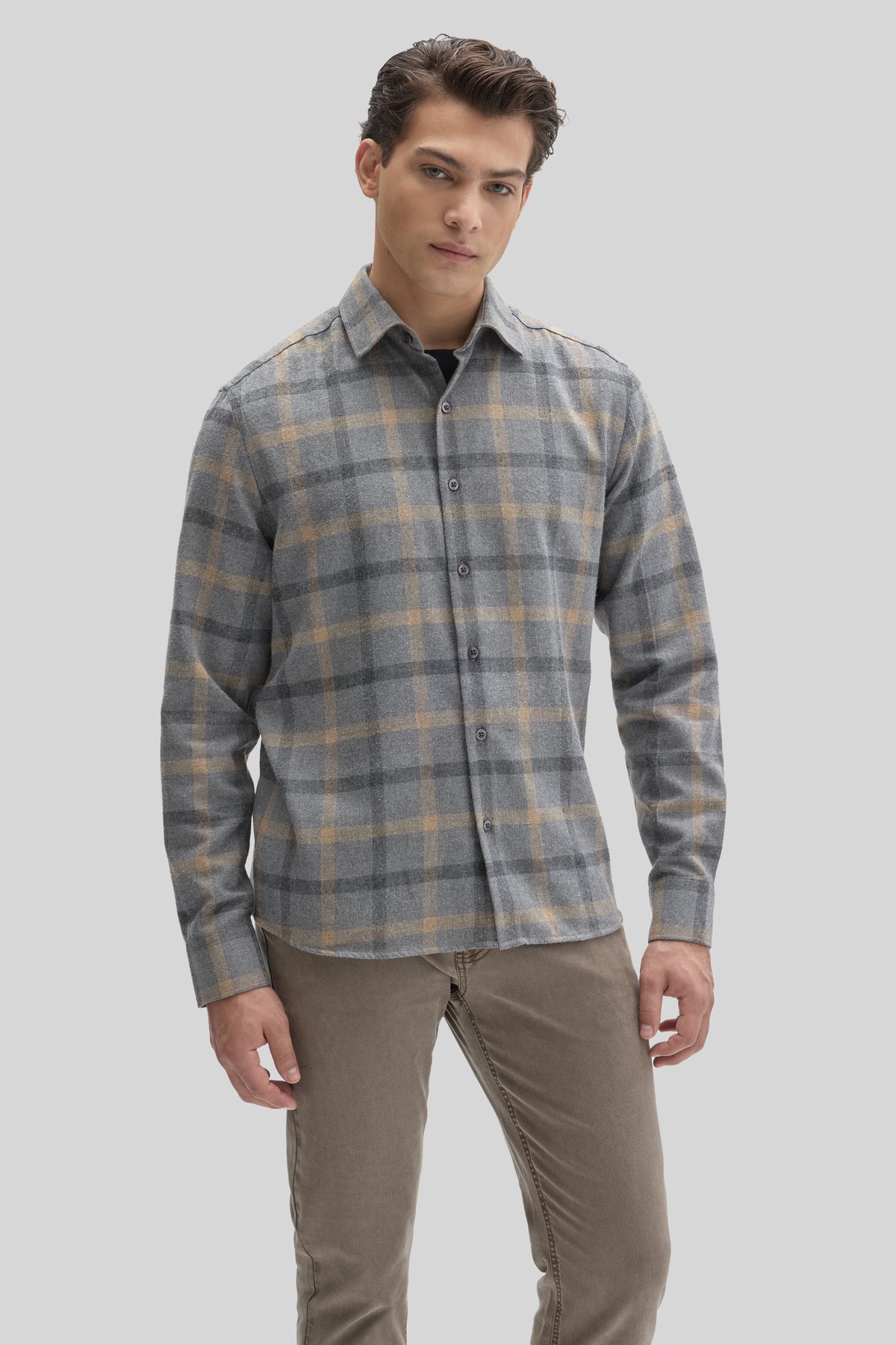 Man wearing gray and tan plaid flannel shirt with button front and collared neckline.