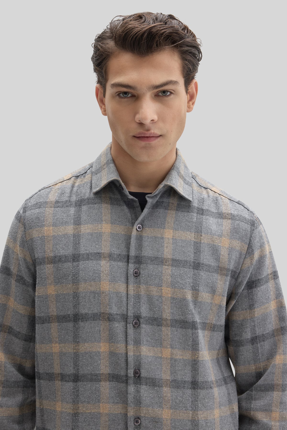 Man wearing gray and tan plaid flannel shirt with button front and collar.