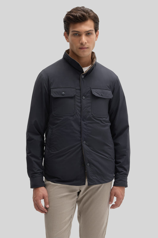 Man wearing black snap jacket with chest pockets and stand collar over beige pants.