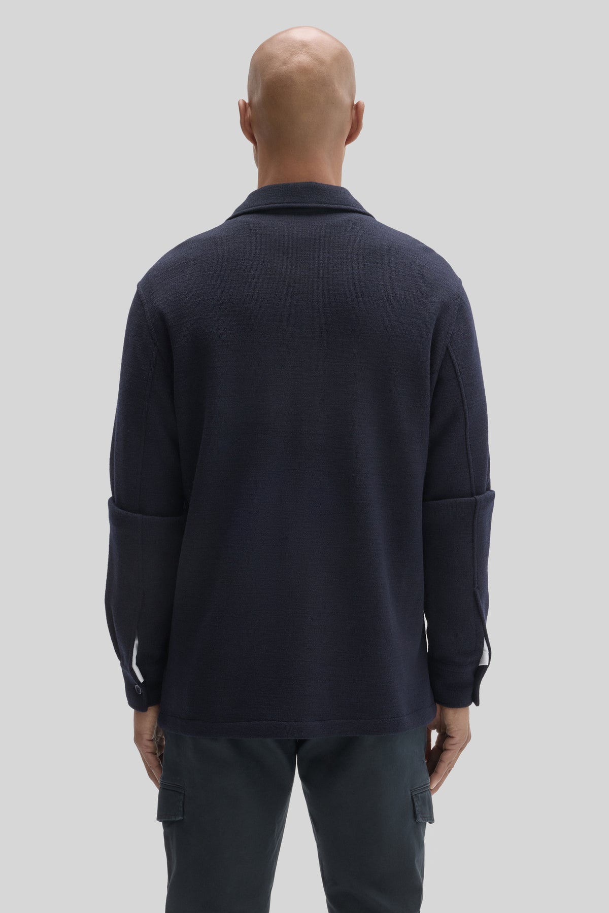 Navy wool overshirt with button cuffs and collar, shown from back on model wearing dark cargo pants.