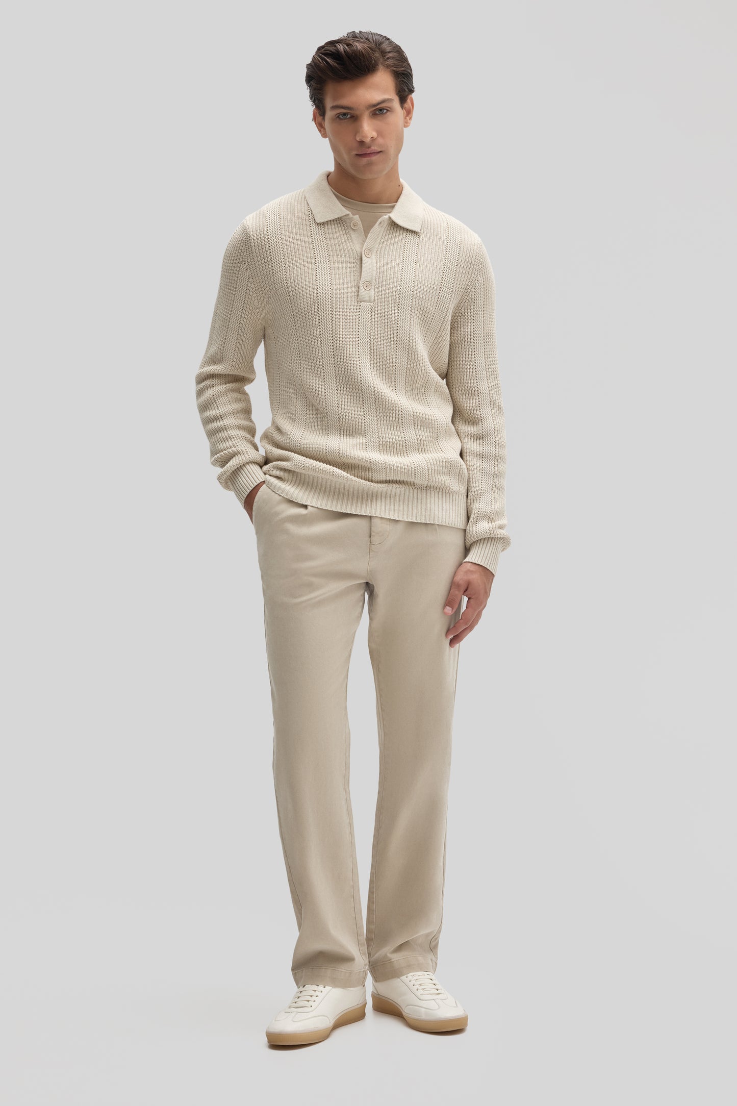 Man wearing cream ribbed long-sleeve polo sweater with collar and matching cream pants.