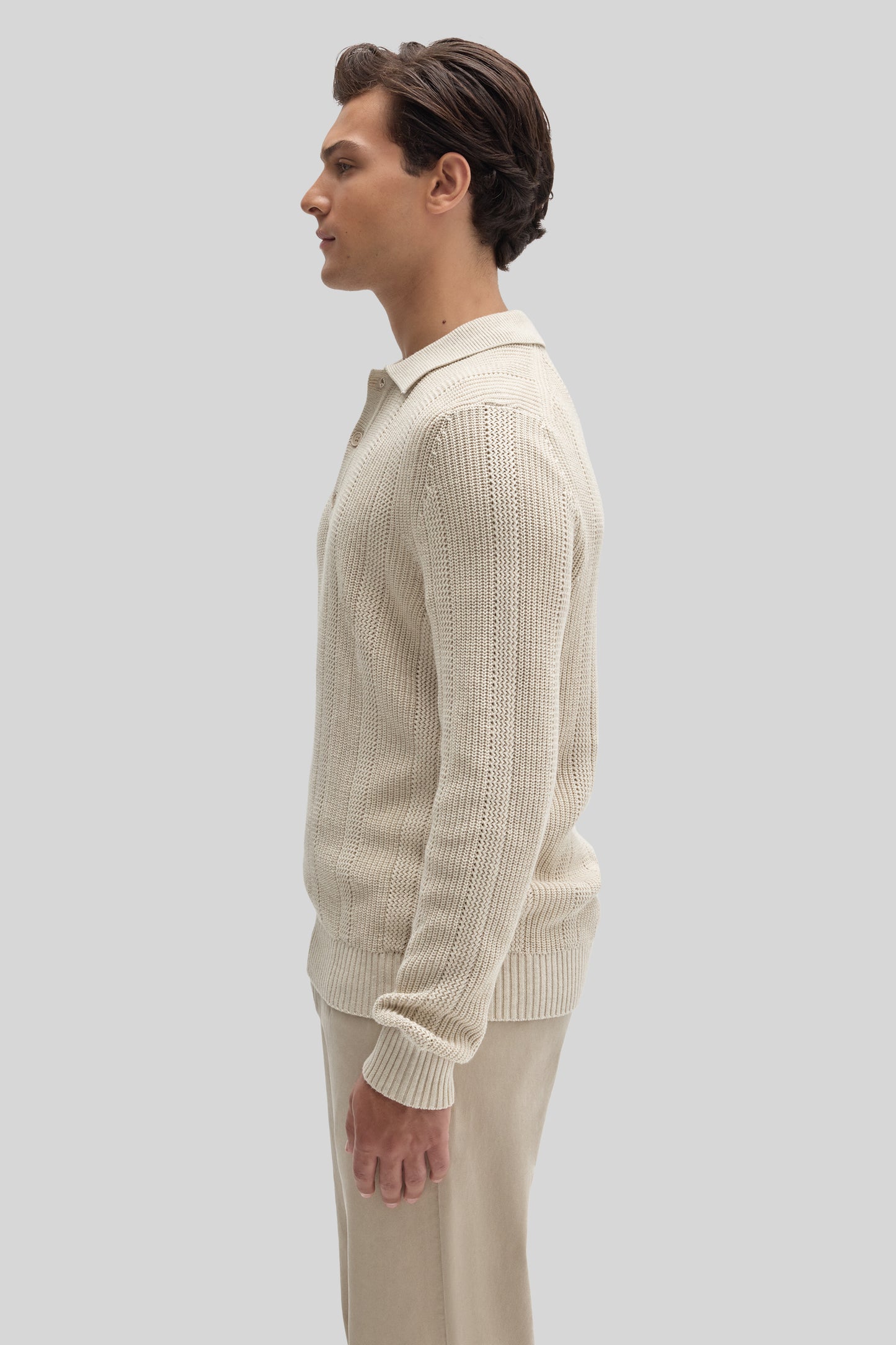Cream knit polo sweater with ribbed texture worn by model in side profile view.