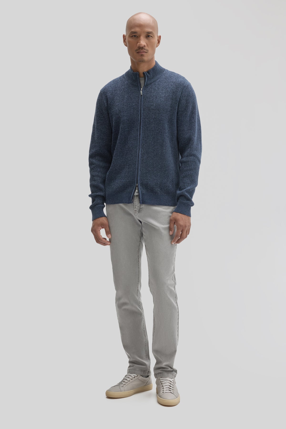 Navy blue full zip mock neck sweater with ribbed cuffs and hem, worn with light gray jeans.