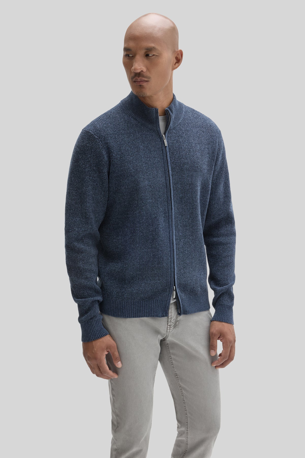 Man wearing navy blue full zip mock neck sweater with ribbed texture over gray pants.