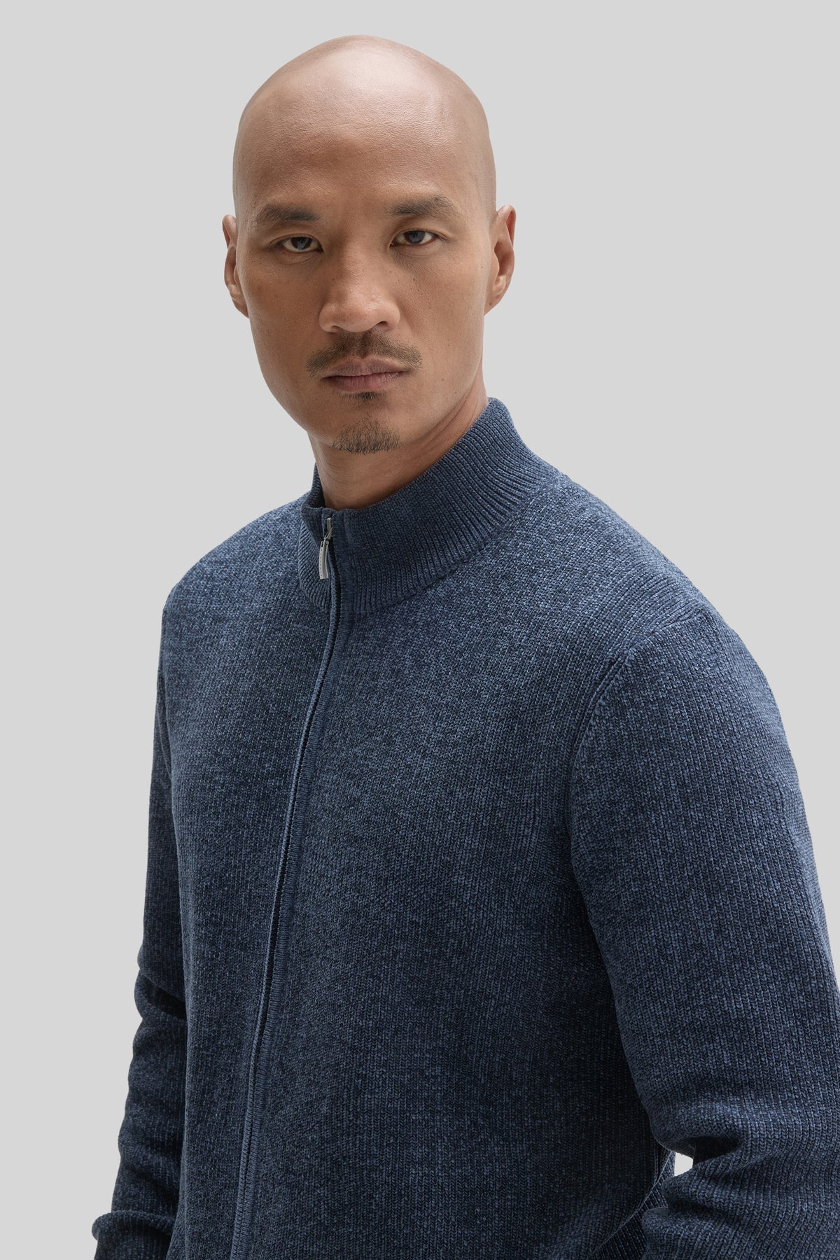Man wearing blue-gray full zip mock neck sweater with ribbed texture.