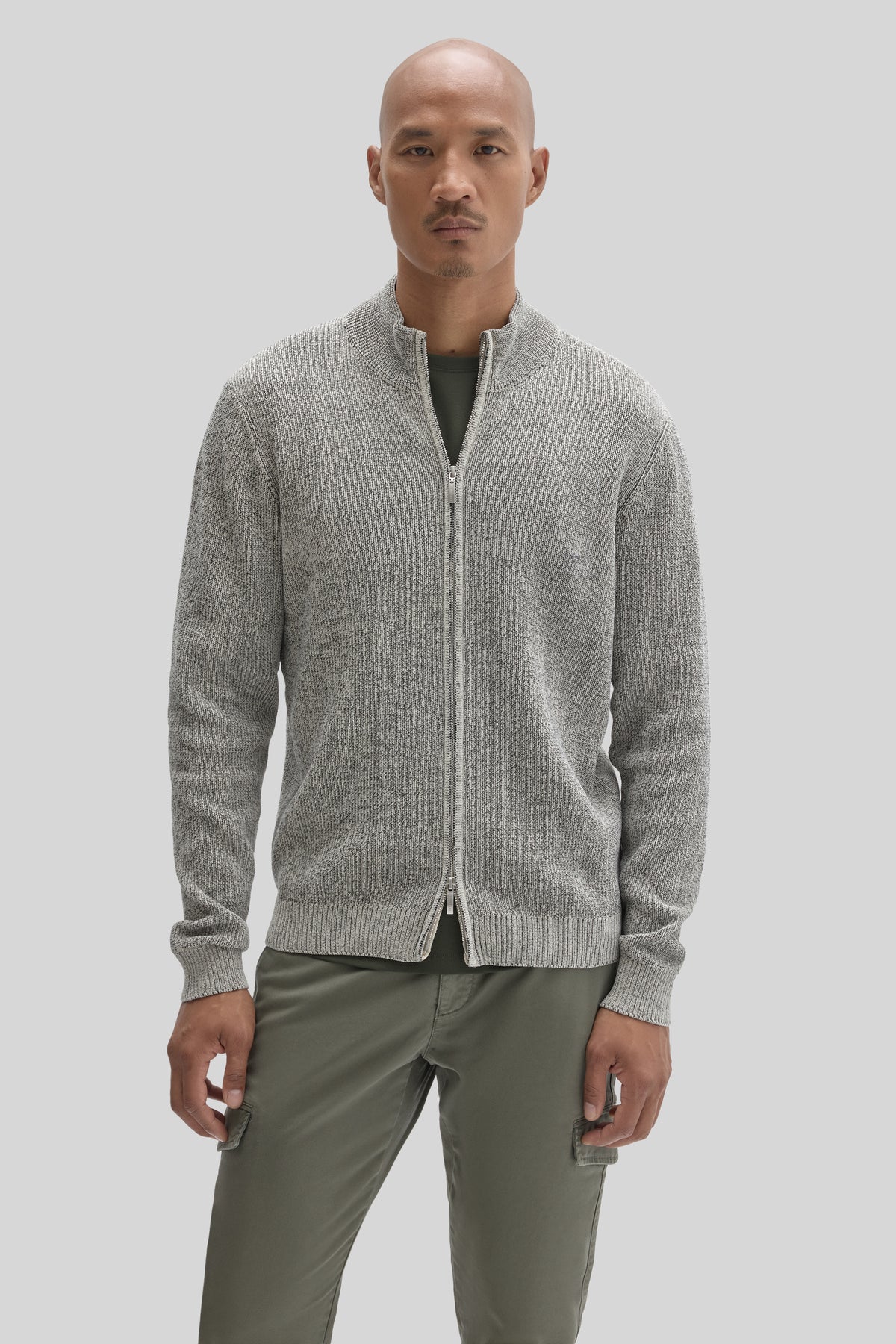 Light gray ribbed full-zip mock neck sweater worn over olive green pants.
