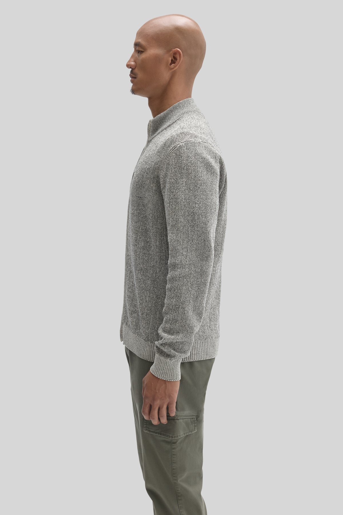 Gray mock neck sweater with full zip and ribbed knit texture worn by a man in side profile view.