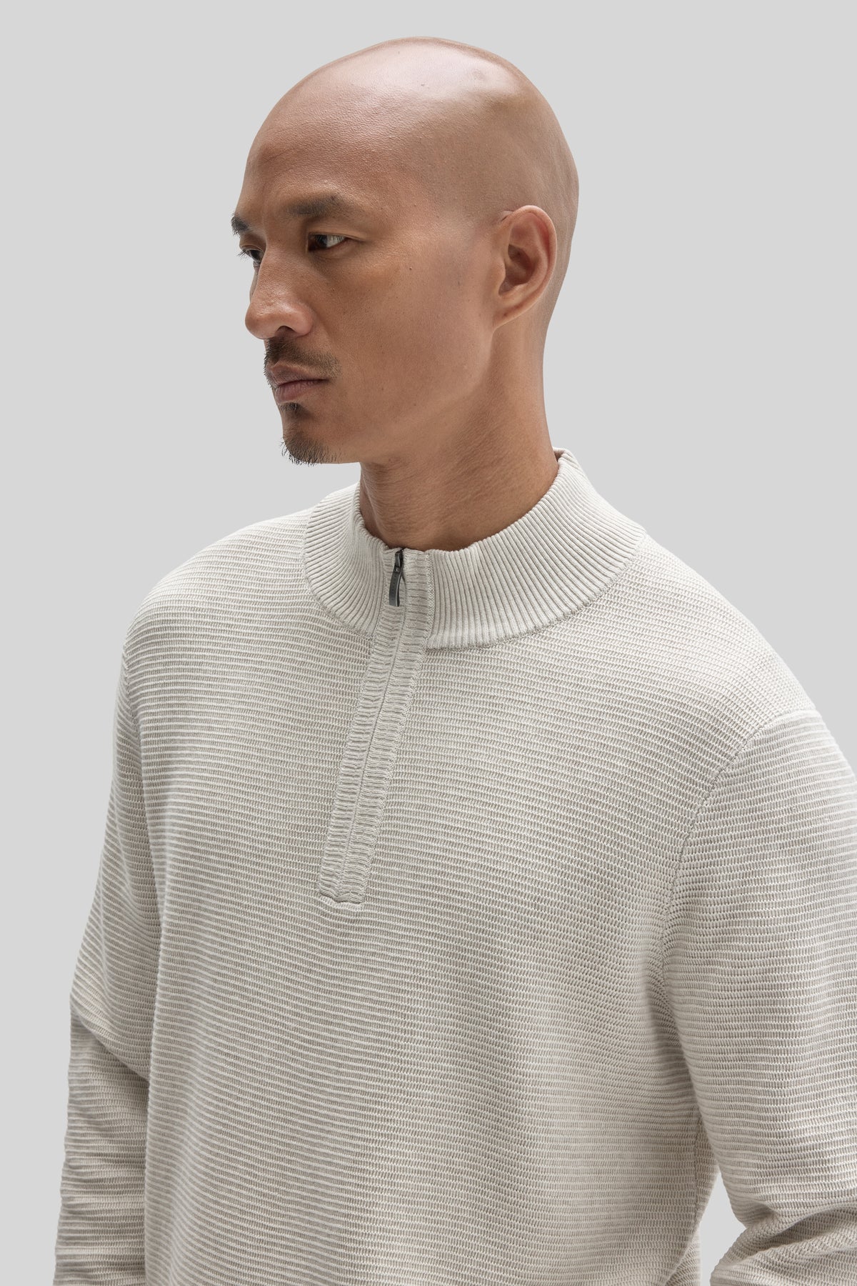 Cream ribbed quarter-zip sweater with mock neck worn by model shown in profile view.