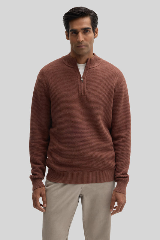 Man wearing a terracotta quarter-zip sweater with ribbed texture and a white undershirt, paired with khaki pants.