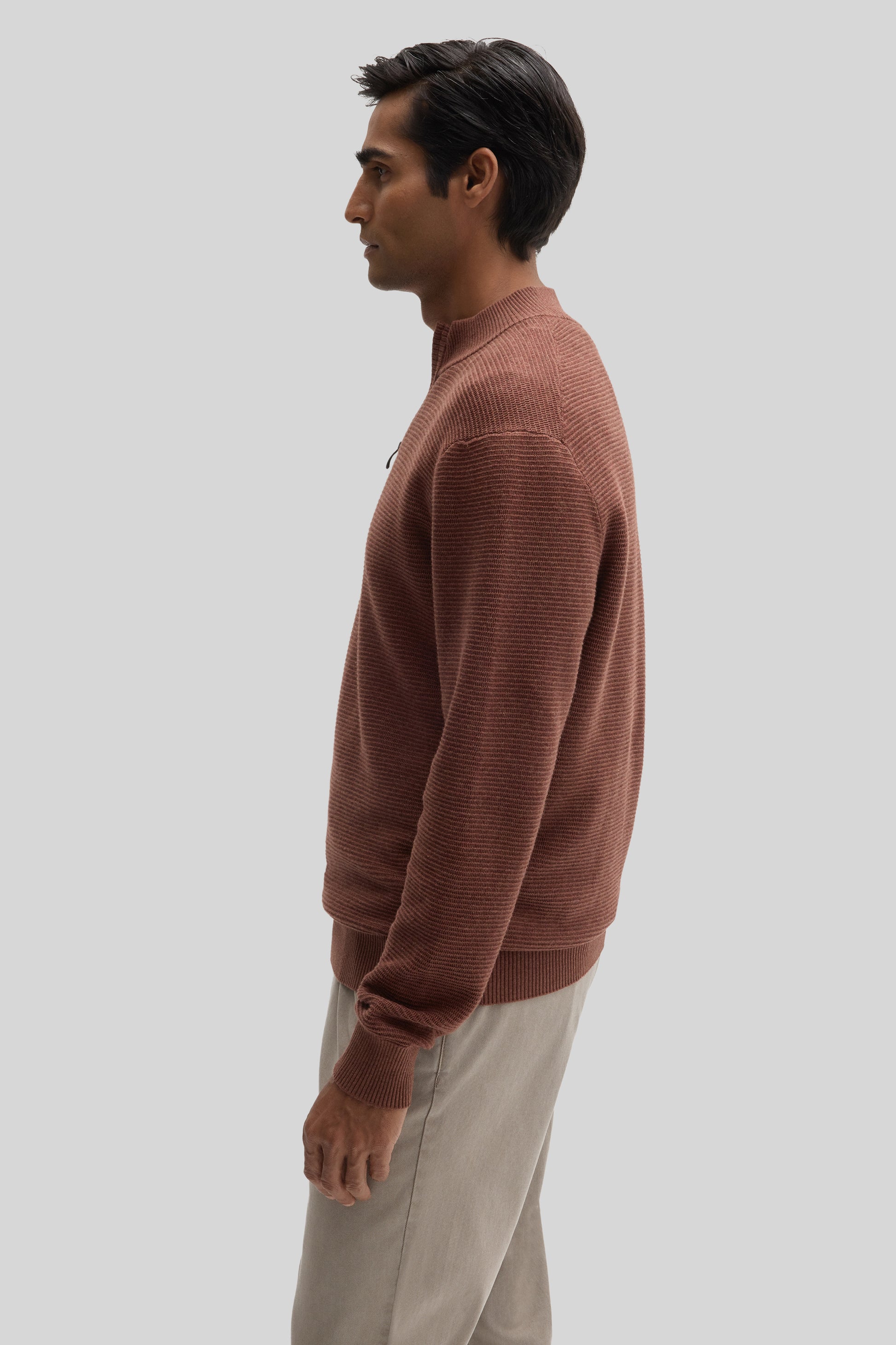 Man wearing mauve ribbed quarter-zip sweater with crew neckline, styled with beige pants.