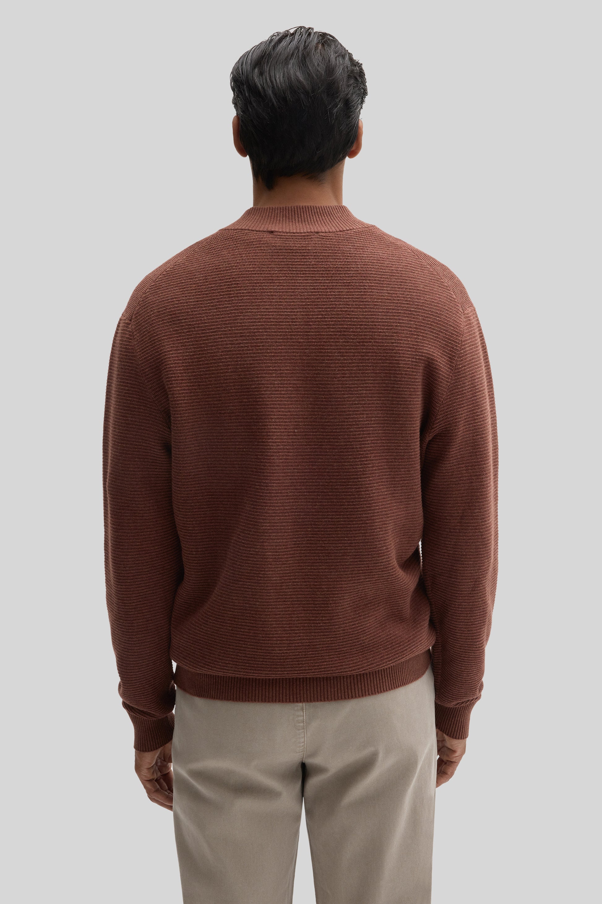 Mauve-brown ribbed quarter zip sweater worn with cream pants, shown from back view.