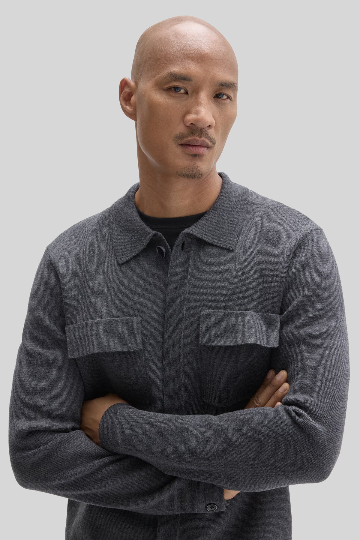 Charcoal gray cardigan with button front, collared neckline, and chest pockets worn by a man.