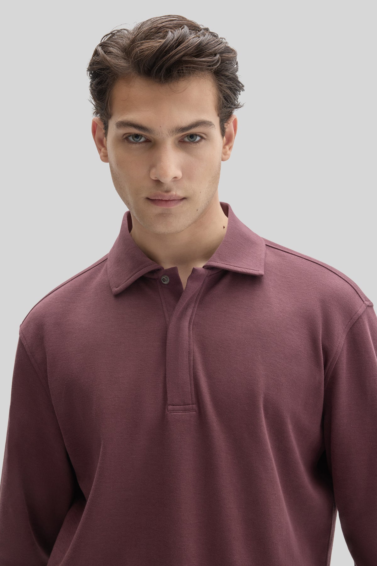 Man wearing mauve snap polo shirt with ribbed texture and collared neckline against neutral background.