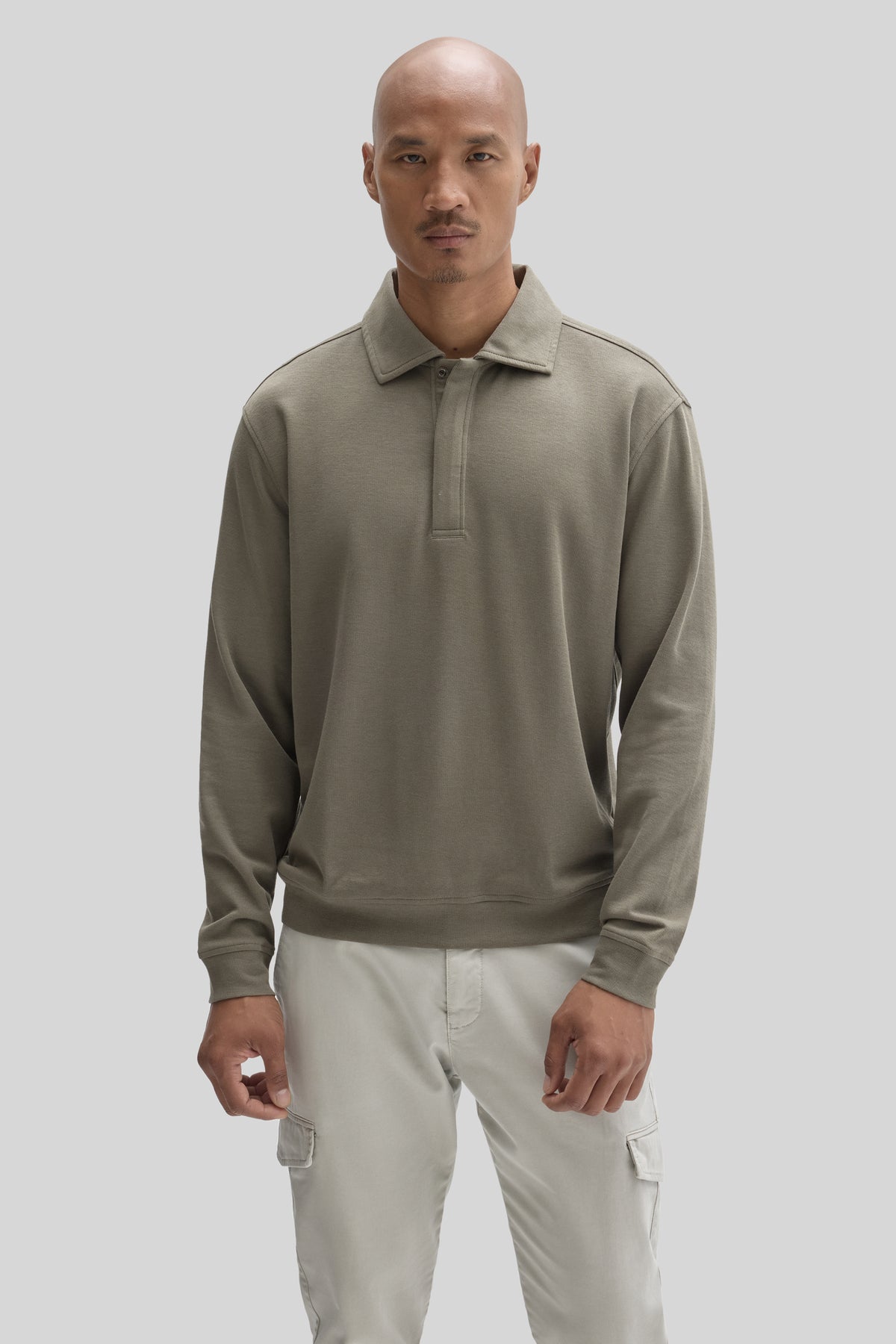 Sage green snap polo with collar worn with cream cargo pants.