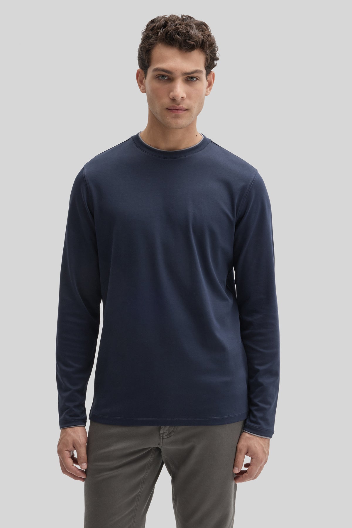 Navy long-sleeve crewneck tee with double-layered neckline worn by man with gray pants.