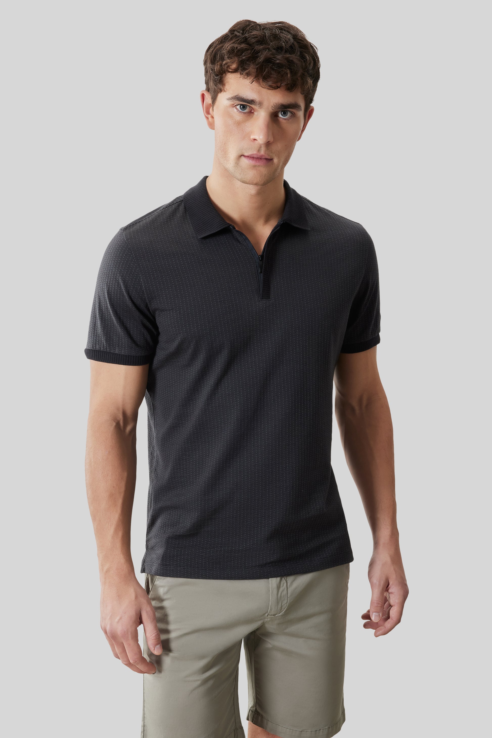 Man wearing charcoal textured short-sleeve polo with covered placket and tan shorts.