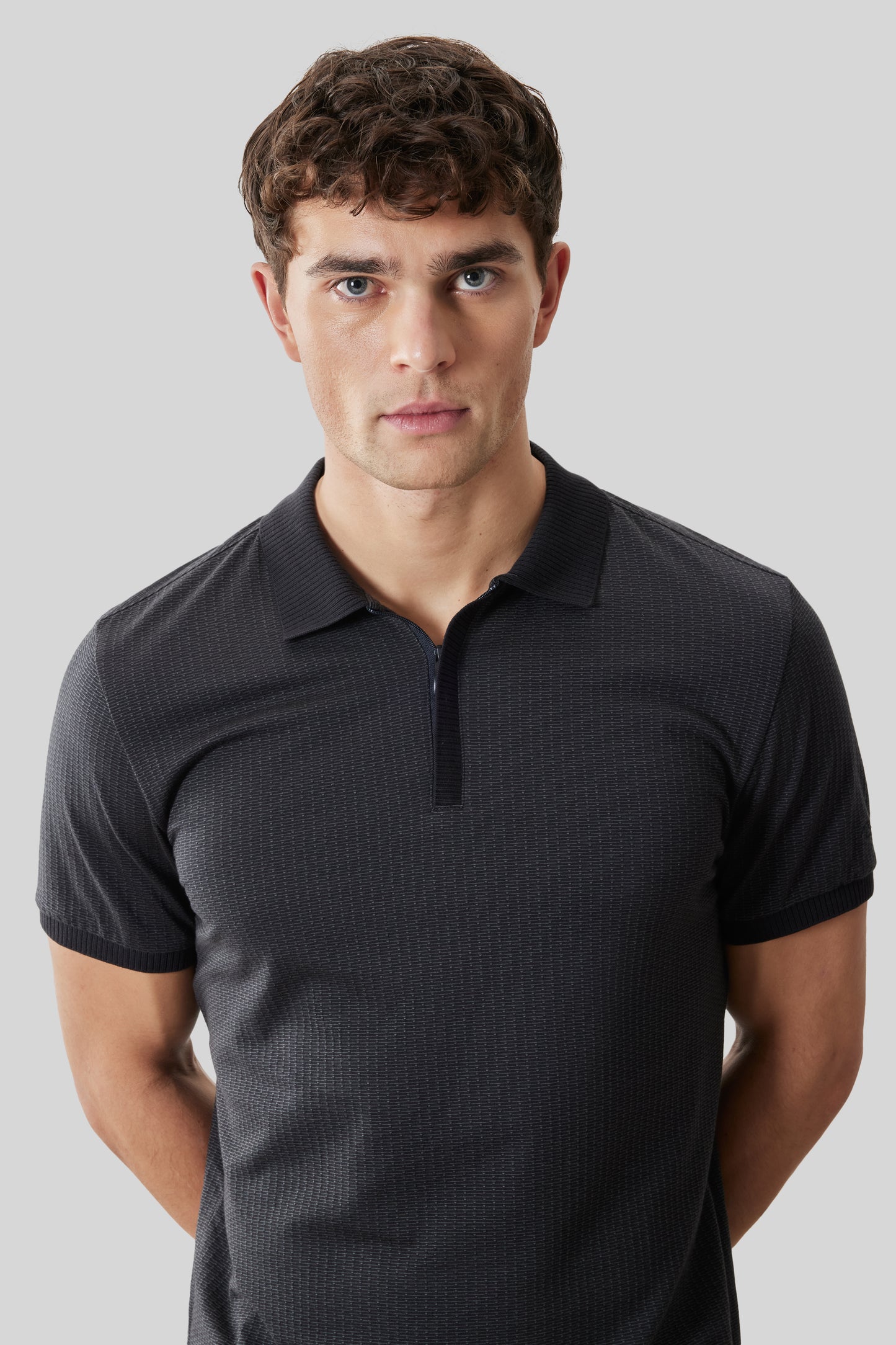 Man wearing charcoal short-sleeve polo shirt with covered placket and textured fabric.