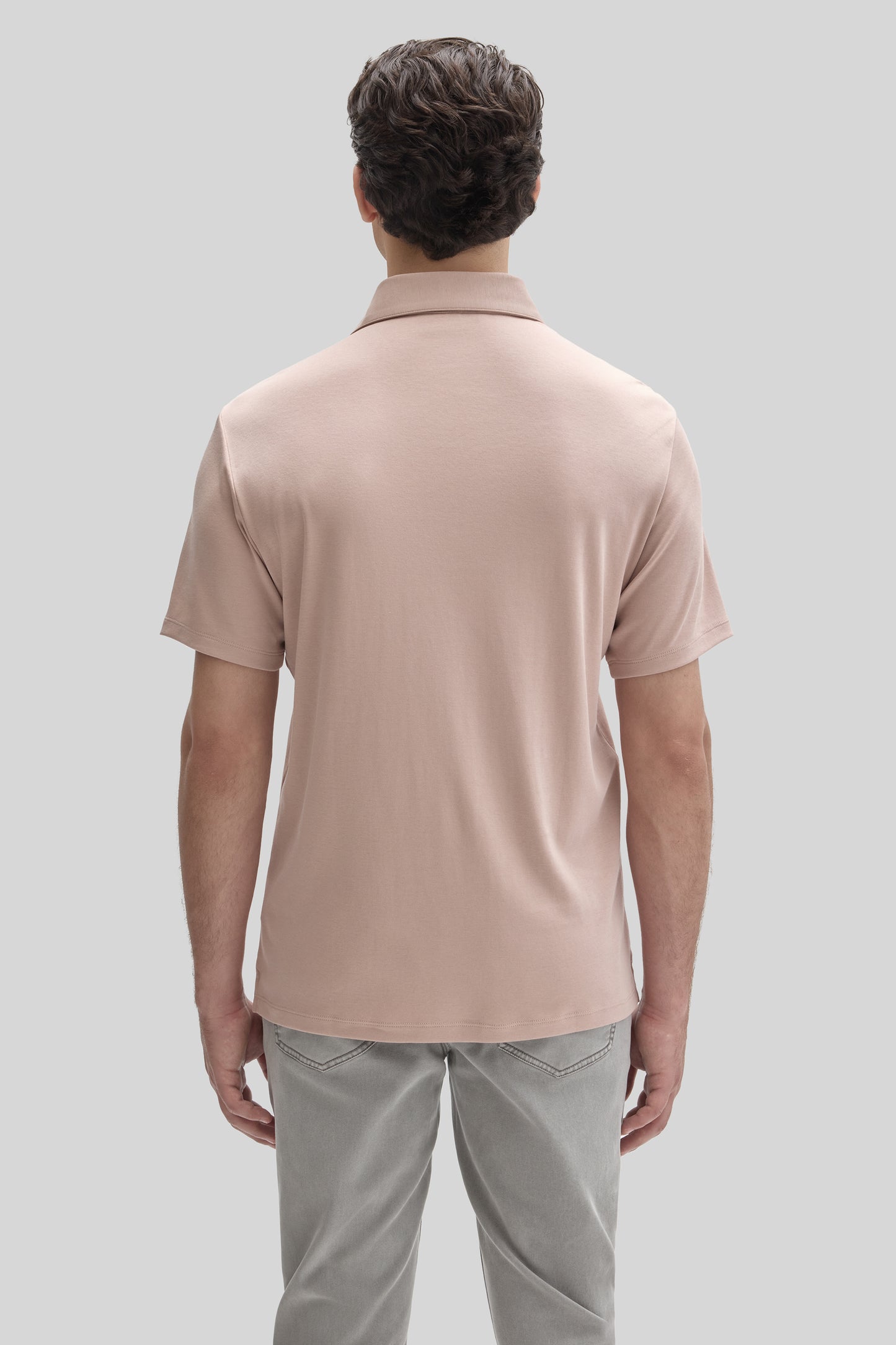 Man wearing a beige short-sleeve polo shirt with collar, shown from behind, paired with gray pants.