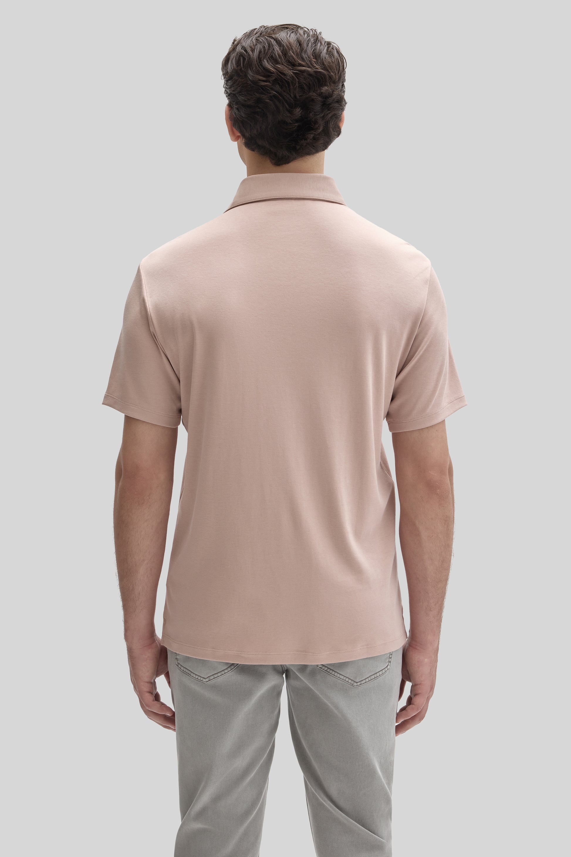 Man wearing a beige short-sleeve polo shirt with collar, shown from behind, paired with gray pants.