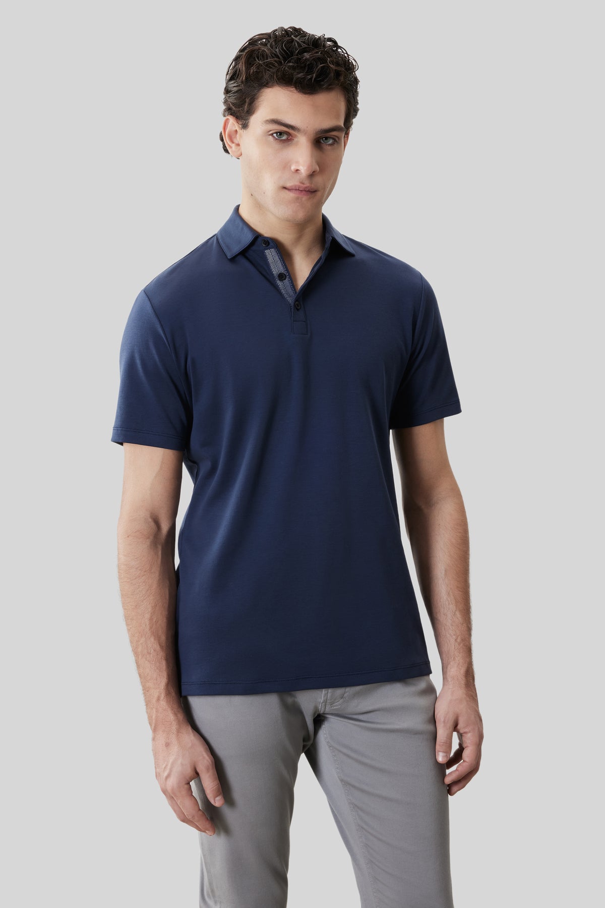 Navy short-sleeve polo shirt with herringbone texture detail on collar, worn with gray pants.