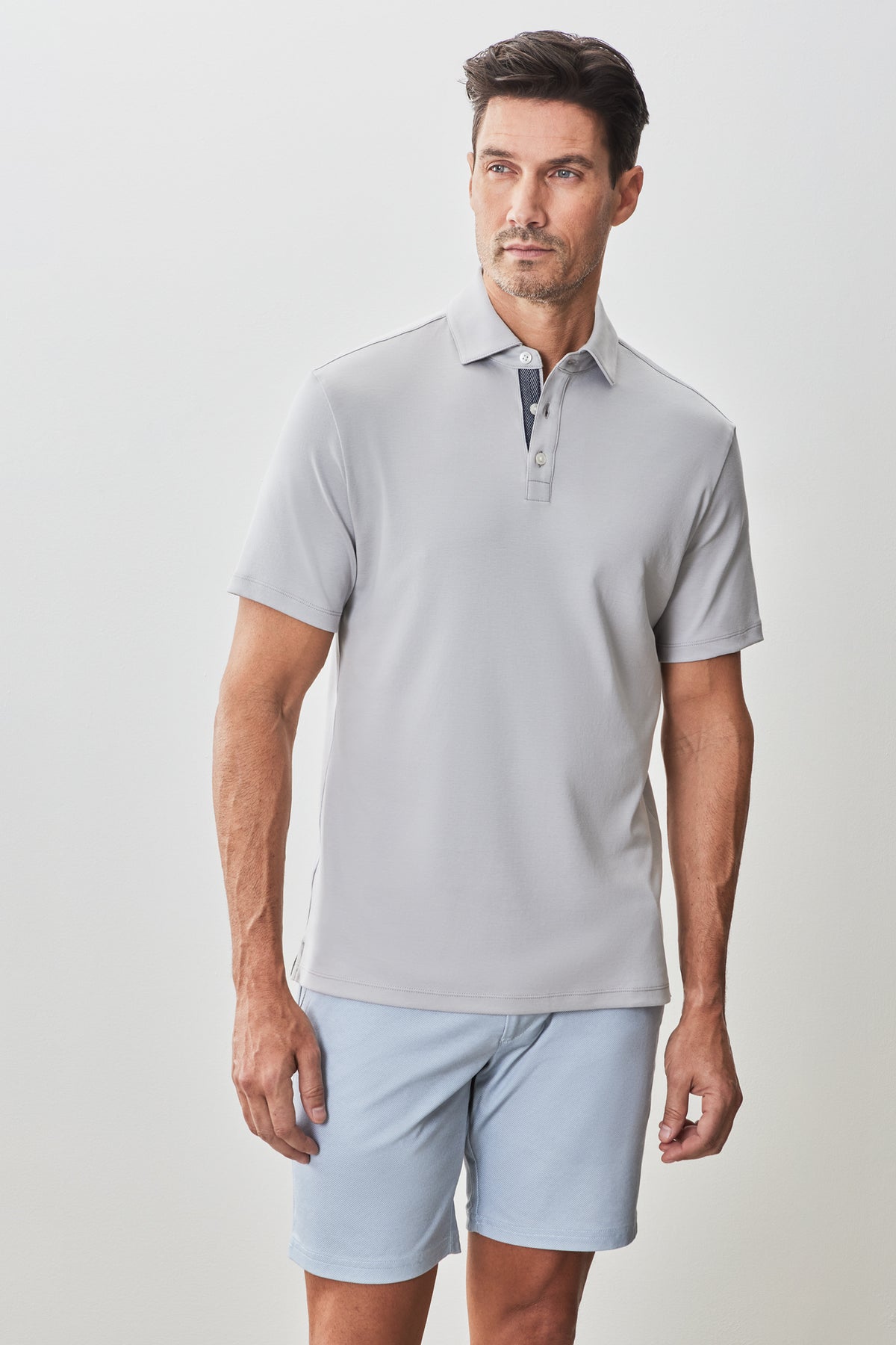Light gray short-sleeve polo shirt with collar and button placket, worn with light blue shorts.