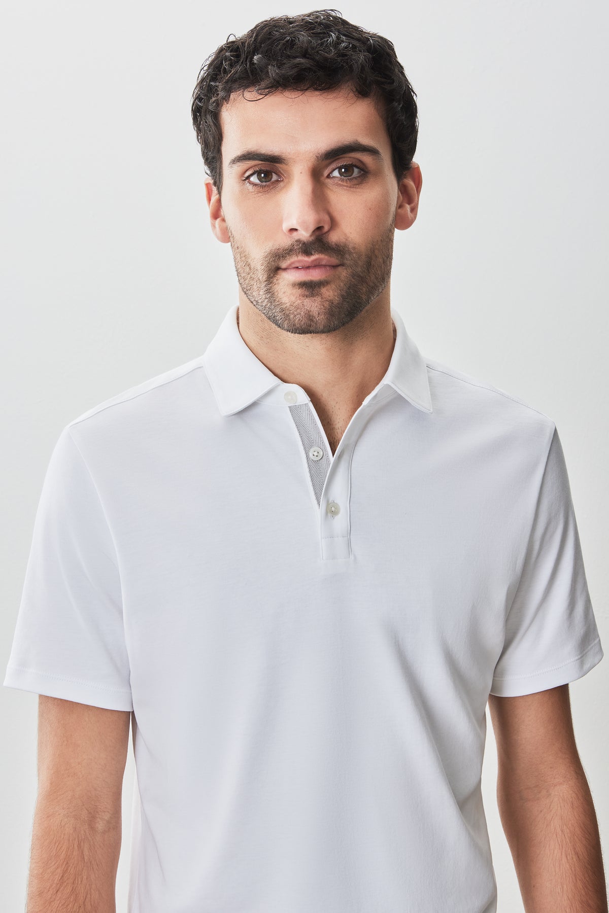 Man wearing white short-sleeve polo shirt with herringbone texture and button placket.
