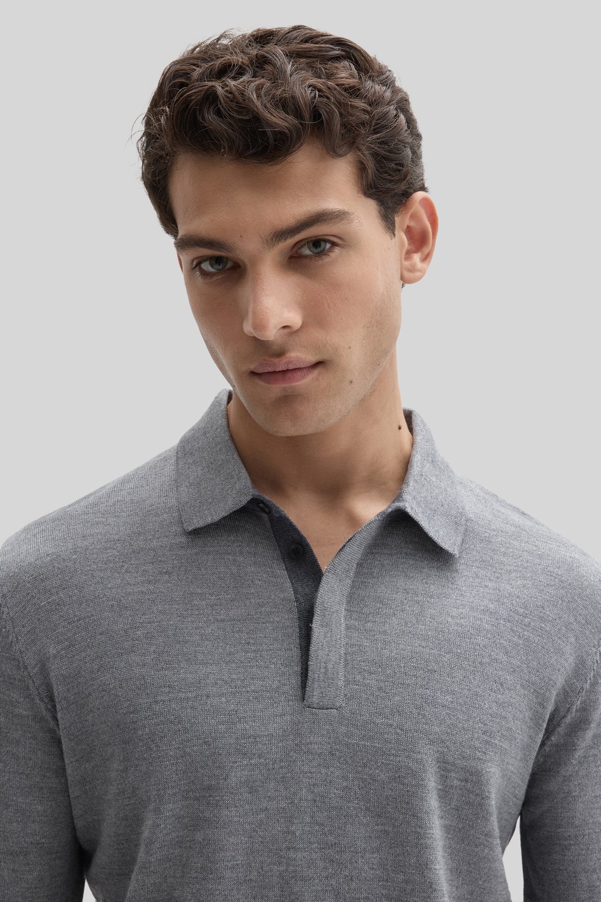 Man wearing gray long sleeve polo sweater with ribbed collar and button placket.