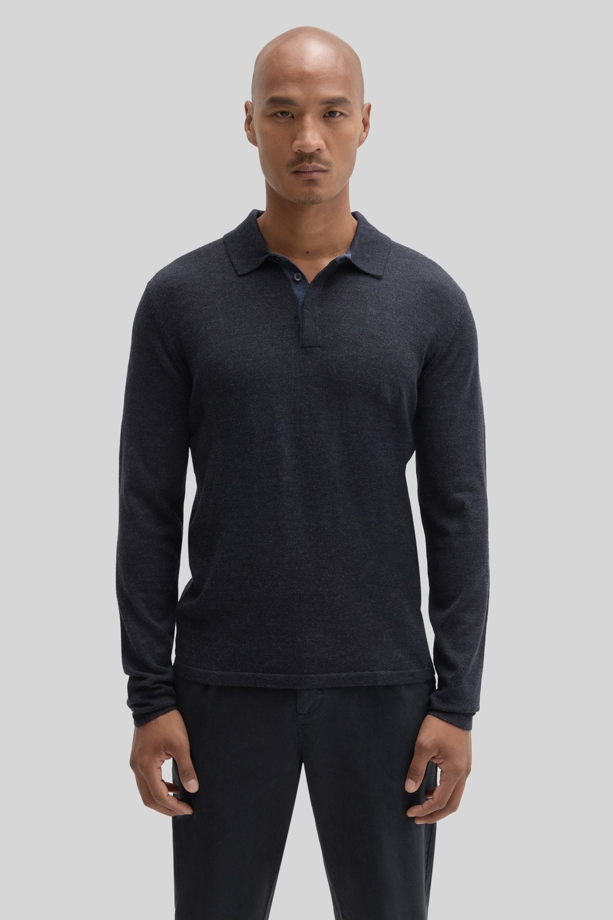 Man wearing charcoal long sleeve polo sweater with collar and button placket.