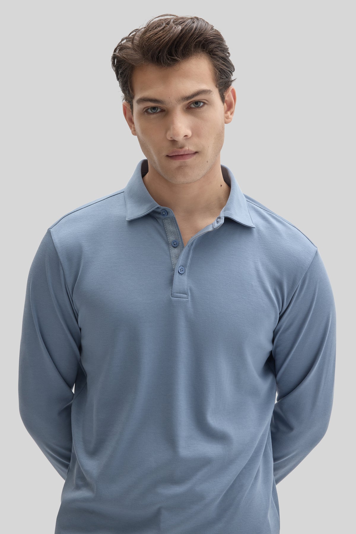 Man wearing light blue long sleeve polo shirt with herringbone texture and button placket.