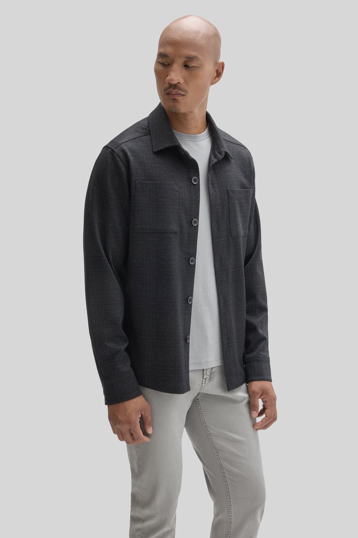 Charcoal gray overshirt with collar, button front, and chest pocket worn over white t-shirt and light jeans.