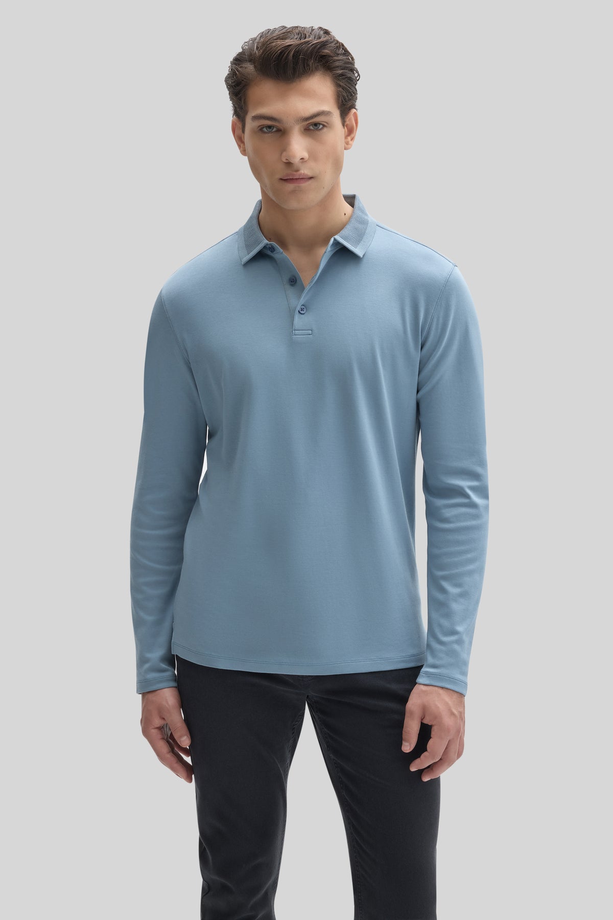 Man wearing light blue long-sleeve polo shirt with textured collar and button placket, paired with black pants.