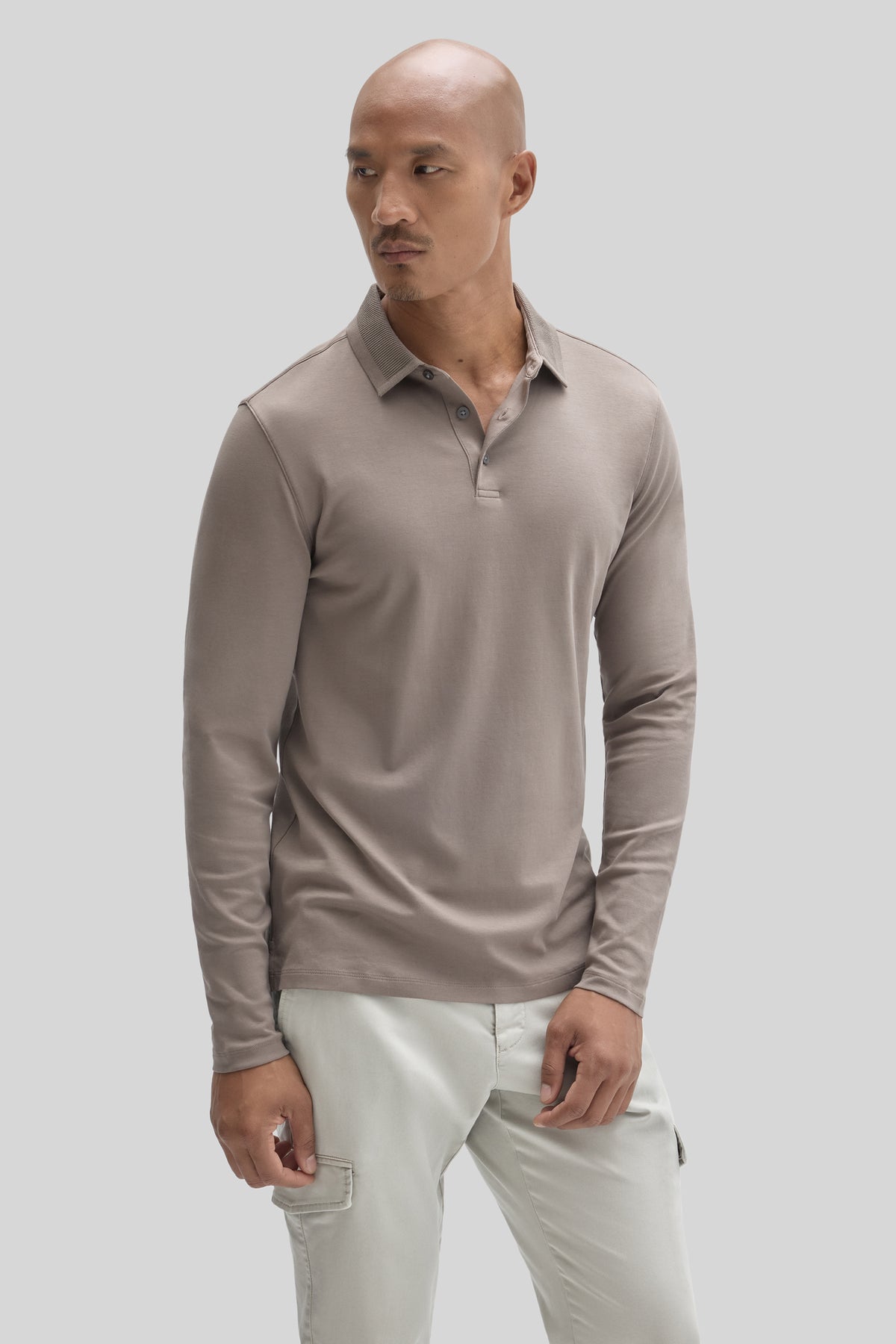 Beige long sleeve polo shirt with textured collar and button placket worn with cream cargo pants.