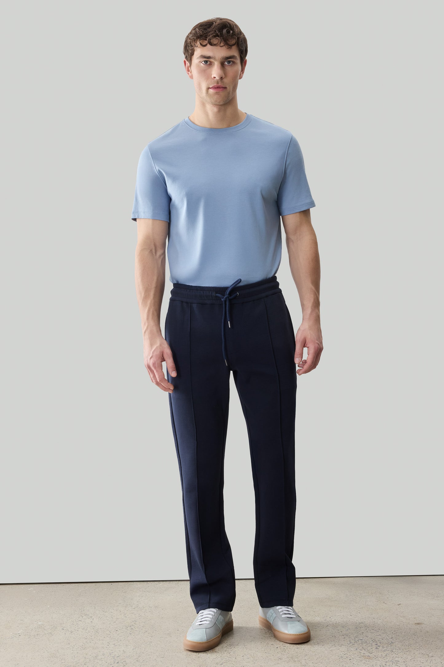 Man wearing light blue t-shirt and black jogger pants with drawstring waist and tapered legs.