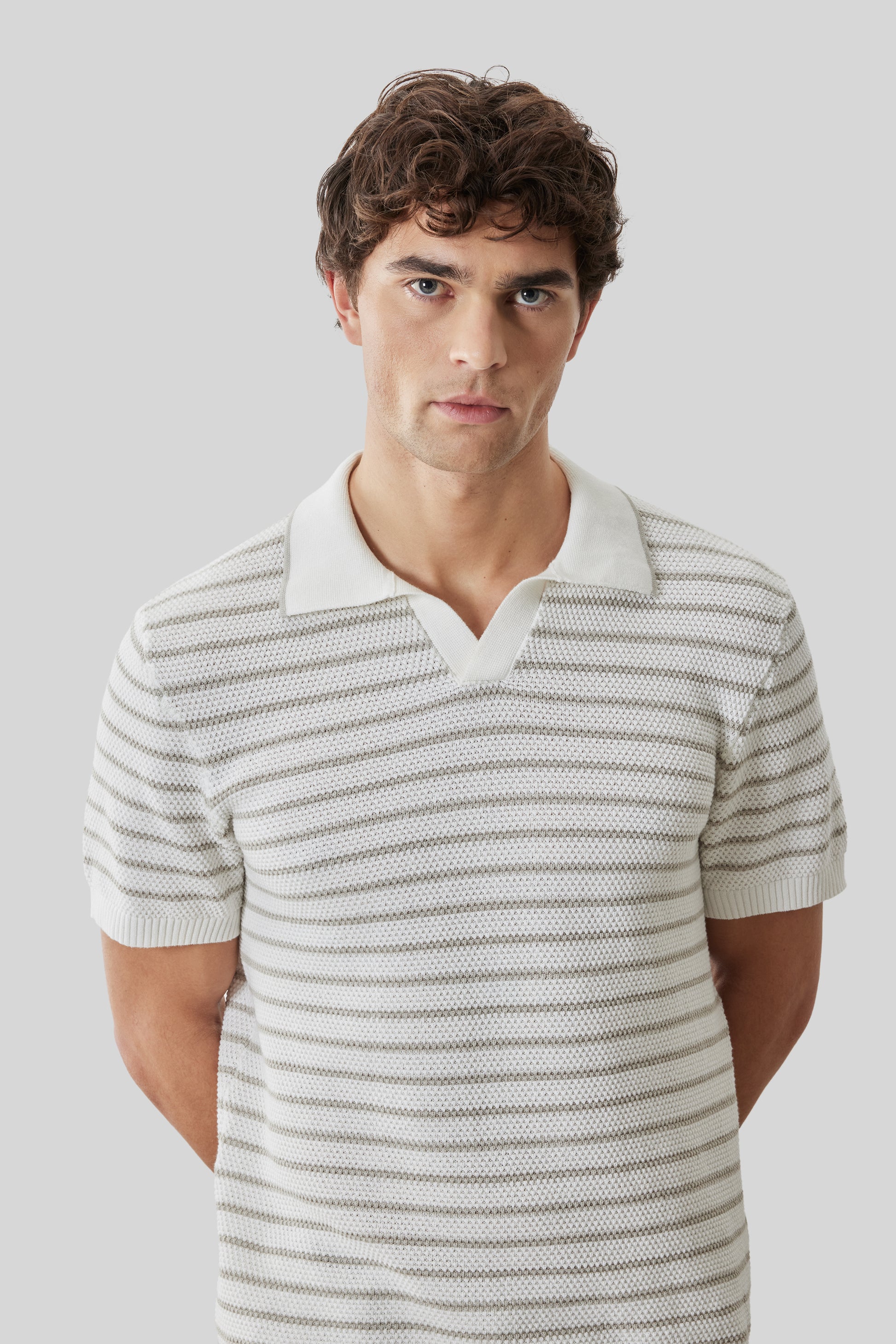 Man wearing cream and gray striped short-sleeve polo with open collar and white trim.