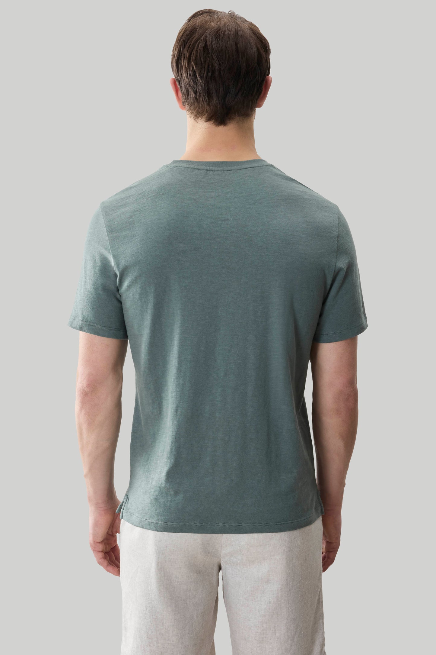 Man wearing sage green short sleeve t-shirt with textured slub fabric, shown from back.