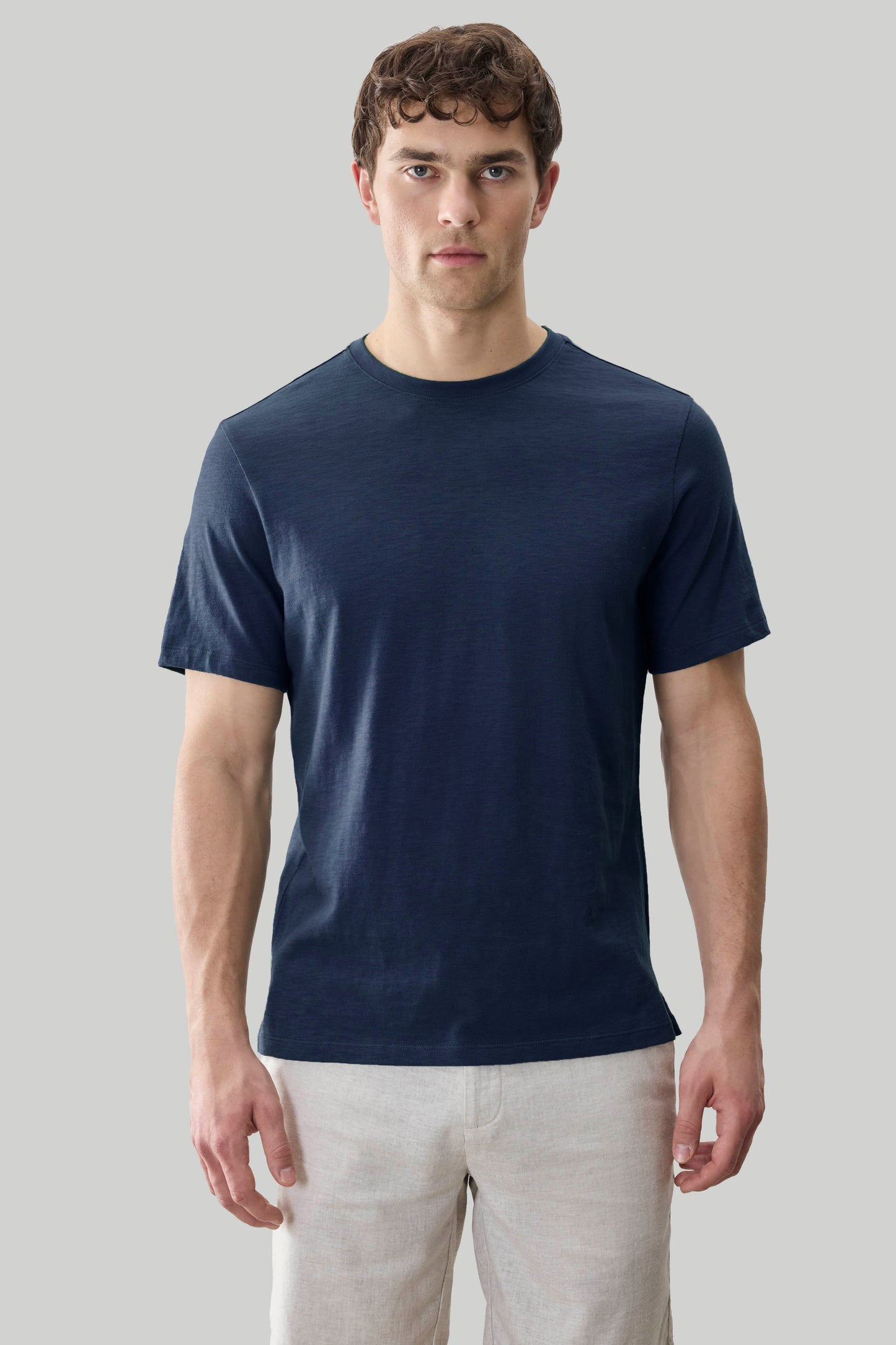 Man wearing navy blue short-sleeve crew neck t-shirt with beige pants.