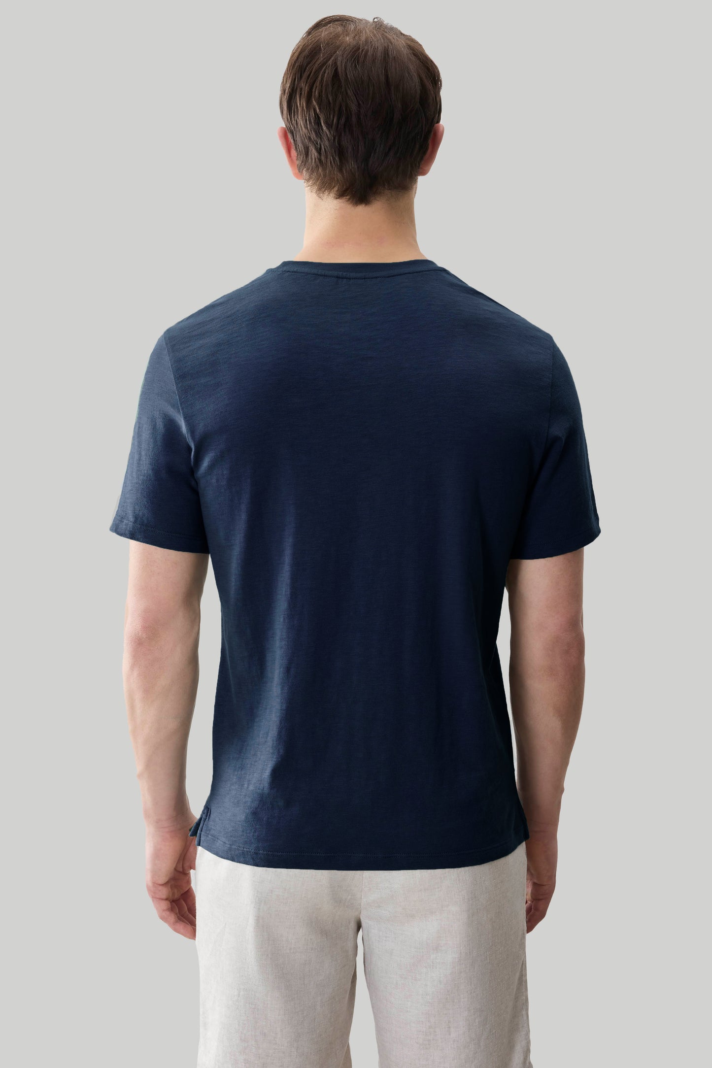 Man wearing dark navy short-sleeve t-shirt and light beige pants, rear view.