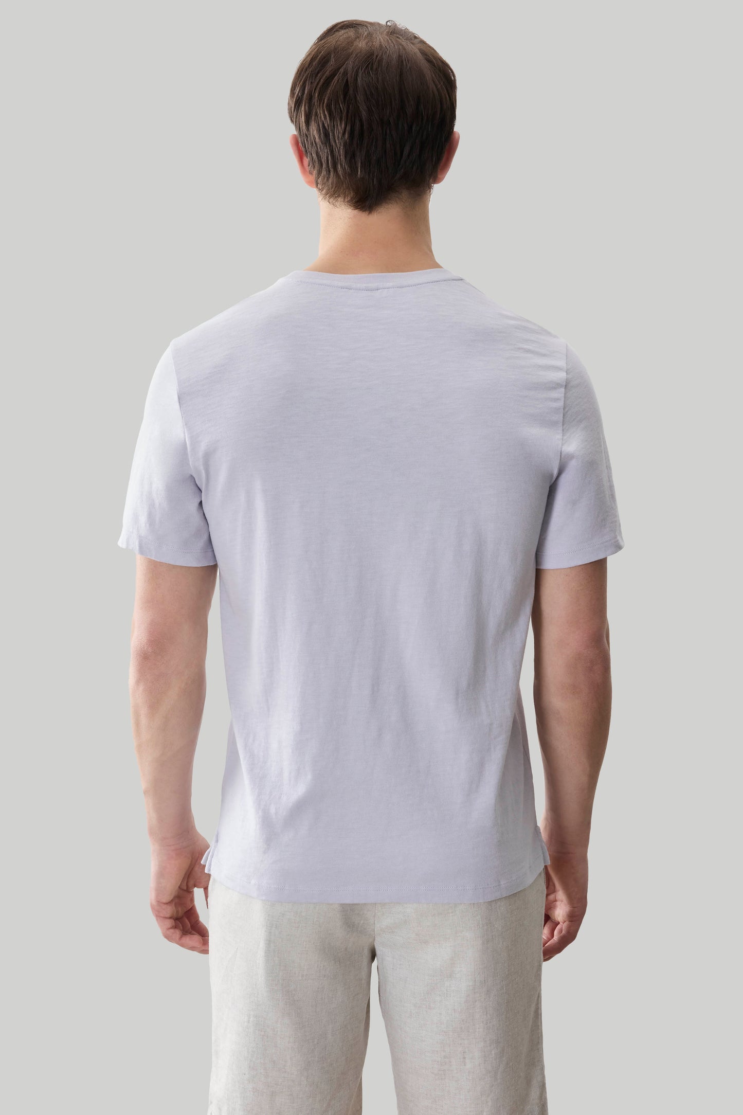 Man wearing light purple short-sleeve t-shirt with textured fabric, shown from back view.