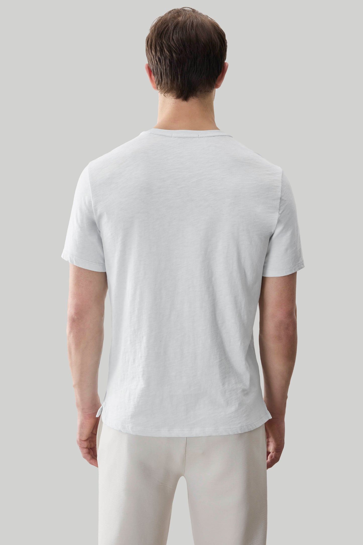 Man wearing light gray short-sleeve t-shirt with crew neckline, shown from back view.