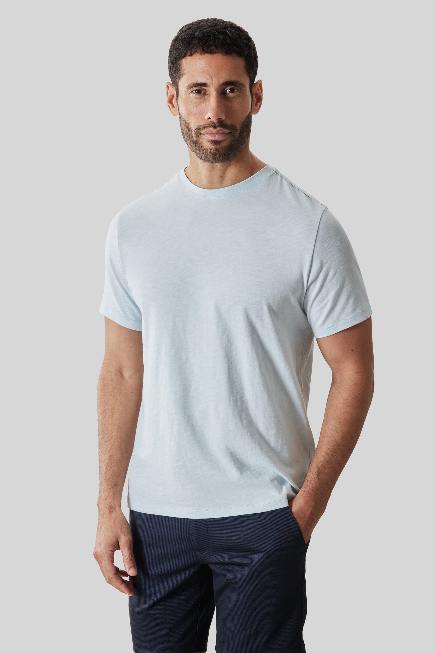 Man wearing light blue short-sleeve crewneck tee with navy pants.