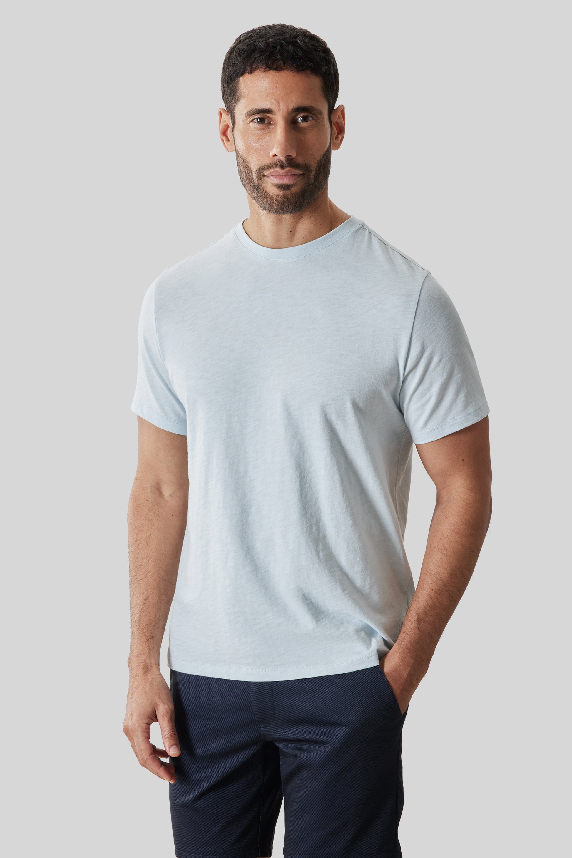 Man wearing light blue short-sleeve crewneck tee with navy pants.