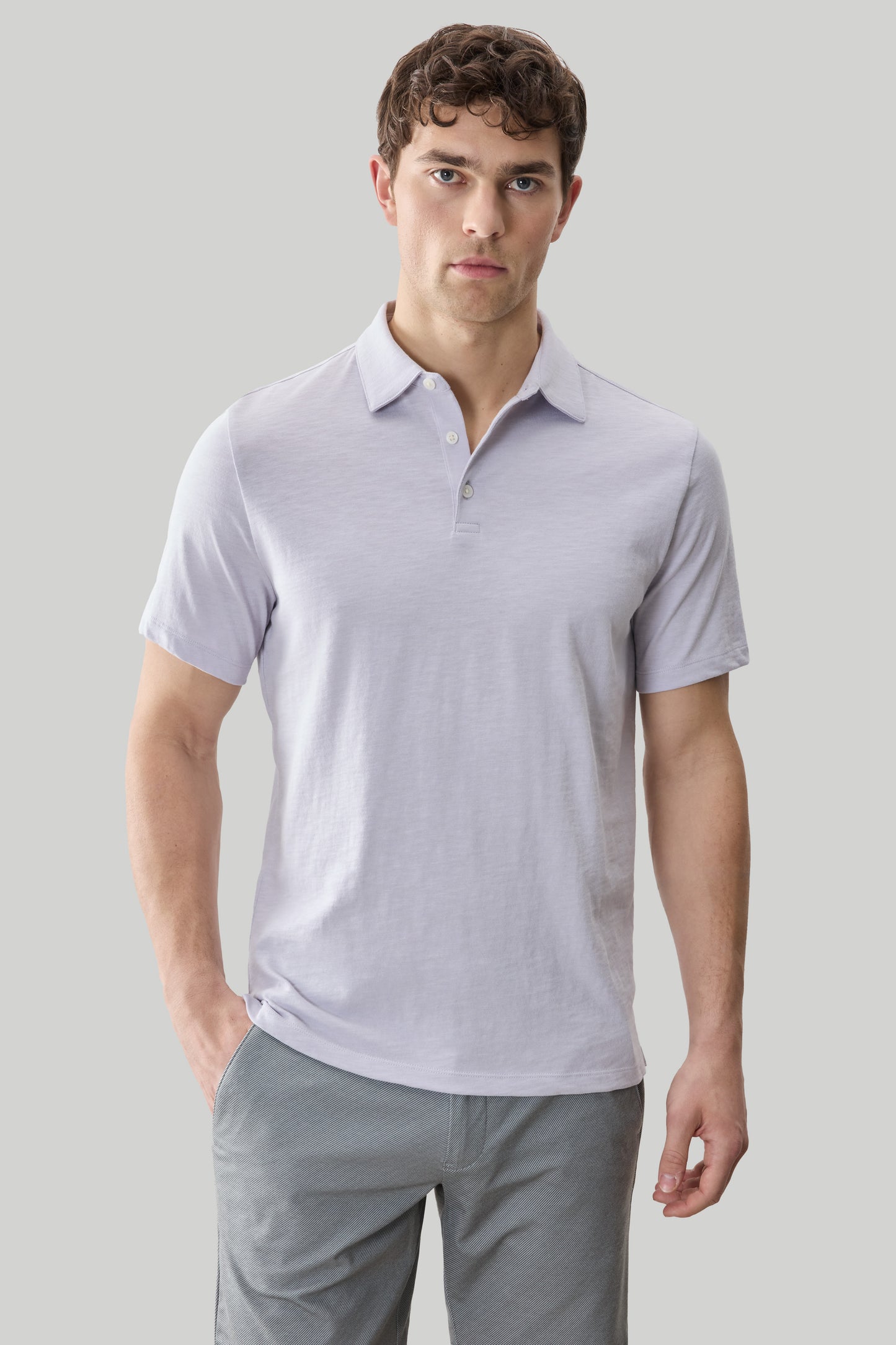 Man wearing light purple short-sleeve polo shirt with collar and button placket, paired with gray pants.