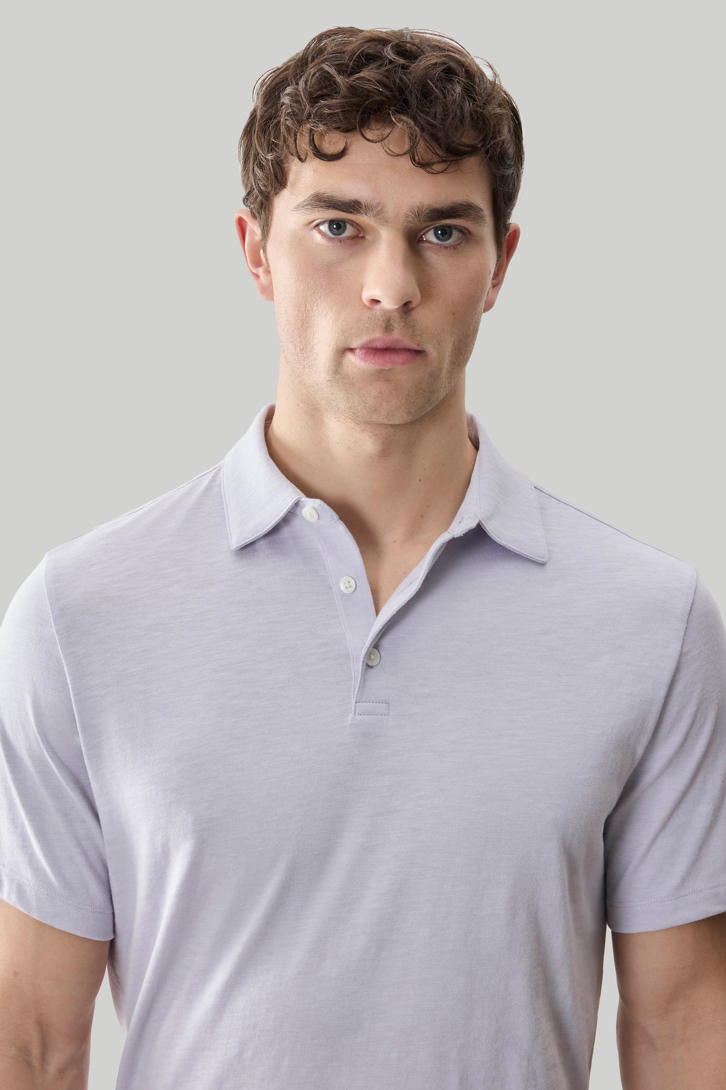 Man wearing a light lavender short-sleeve polo shirt with button placket and collar.