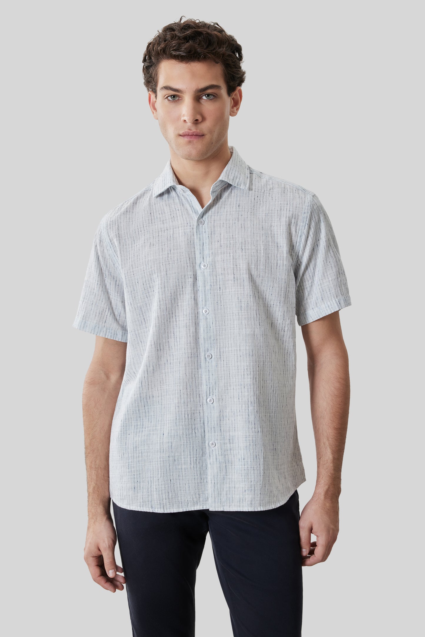 Man wearing light gray short-sleeve button-up shirt with vertical texture pattern and white buttons.